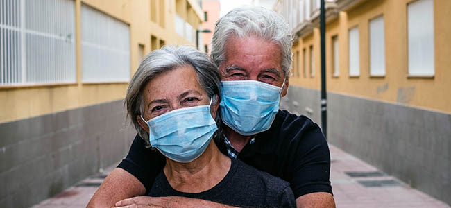 A couple wearing face masks hugging in the street.
