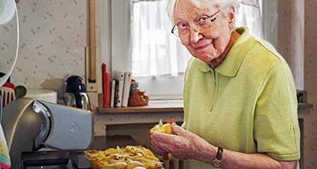 An elderly lady preparing a meal at home.
