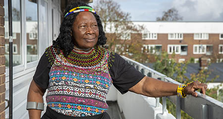 A woman standing on a balcony outside a flat.