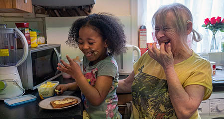 A woman making toast with her grandchild.